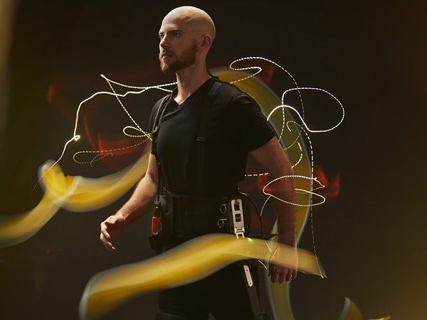 A person wearing a high-tech suit surrounded by swirling light trails.