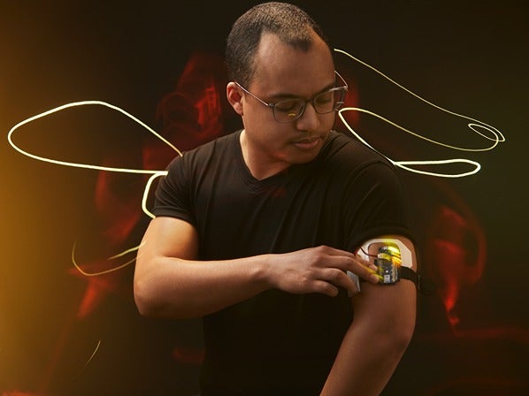 Person adjusting an electronic device on their arm with swirling glowing lines in the background.