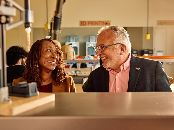 Two people smiling in a workplace.