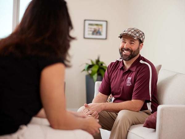 Two people conversing on a sofa in a cozy room.