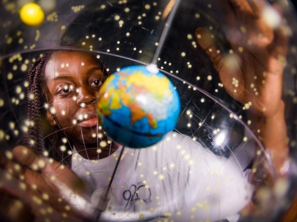 Person observing a celestial sphere with a miniature Earth model.