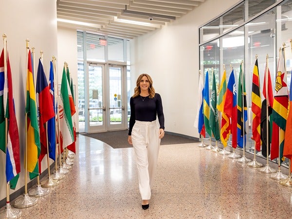 A woman walks down a corridor lined with international flags.