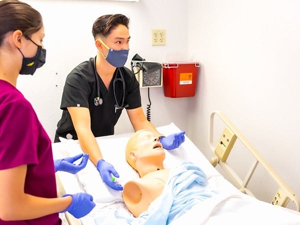 Medical students practicing on a manikin in a clinical setting.