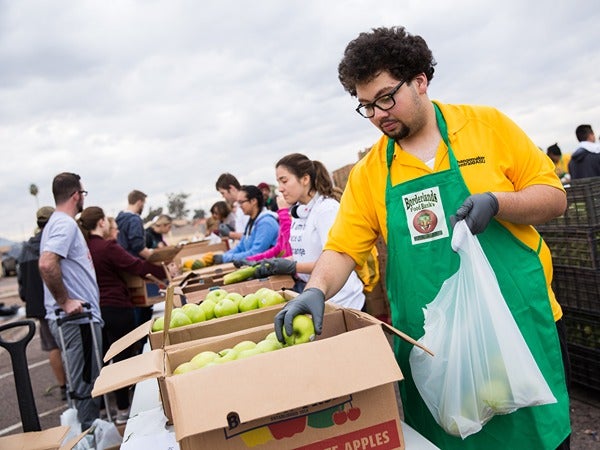 Volunteers packing apples at an outdoor event.