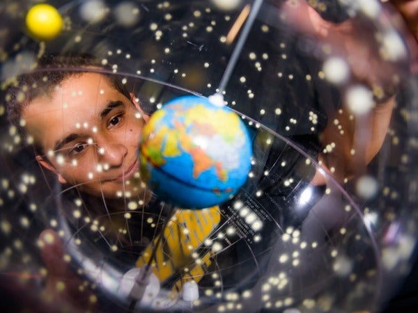 Person looking at a model solar system with Earth prominently visible.