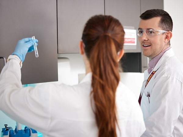 Two people in a lab, one holding a test tube.