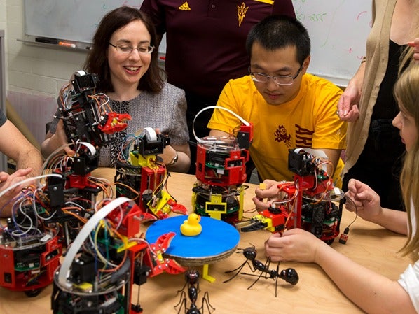 People interacting with small robots on a table.