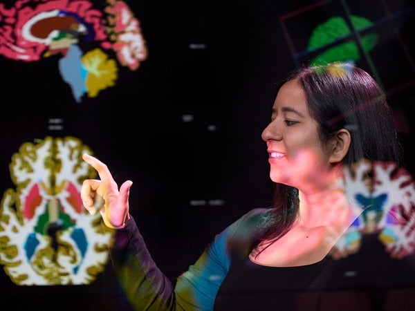 Person interacting with a screen displaying colorful brain scans.
