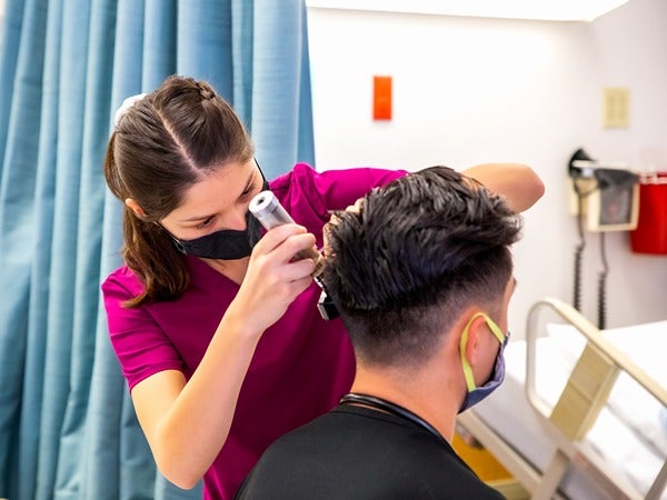 Healthcare worker examines a patient's scalp in a clinical setting.