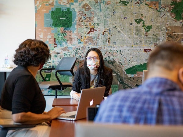 People meeting around a table with a large map in the background.