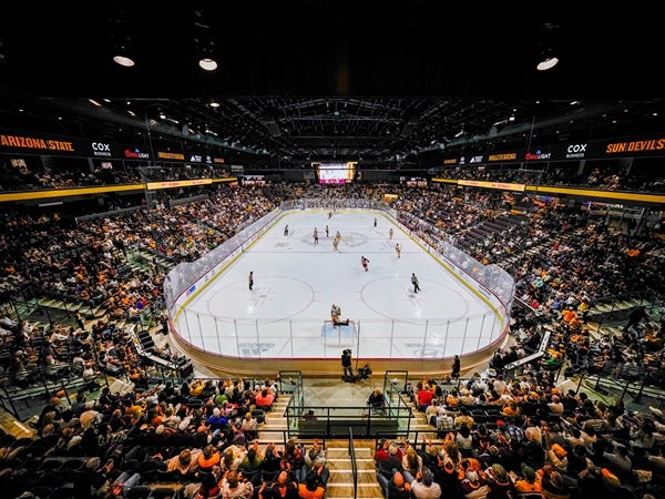 A crowded hockey arena with a game in progress.