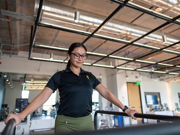 A woman walking on a treadmill in a modern gym.