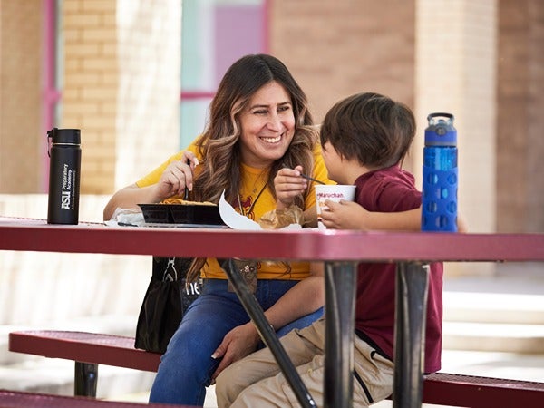 Woman and child eating at a picnic table.