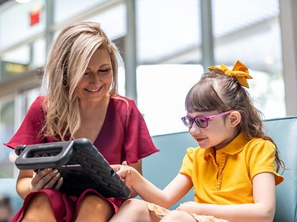 An adult and a child looking at a tablet together indoors.