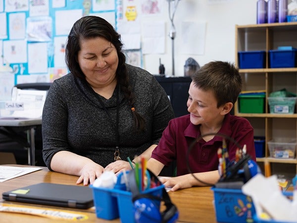 A woman and a young boy smiling in a classroom.
