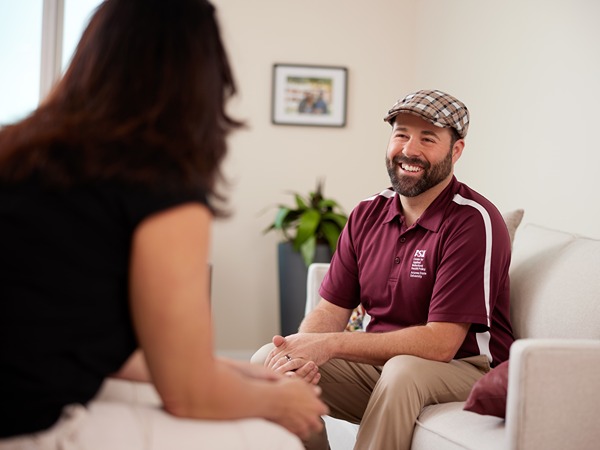 Two people conversing on a sofa in a cozy room.